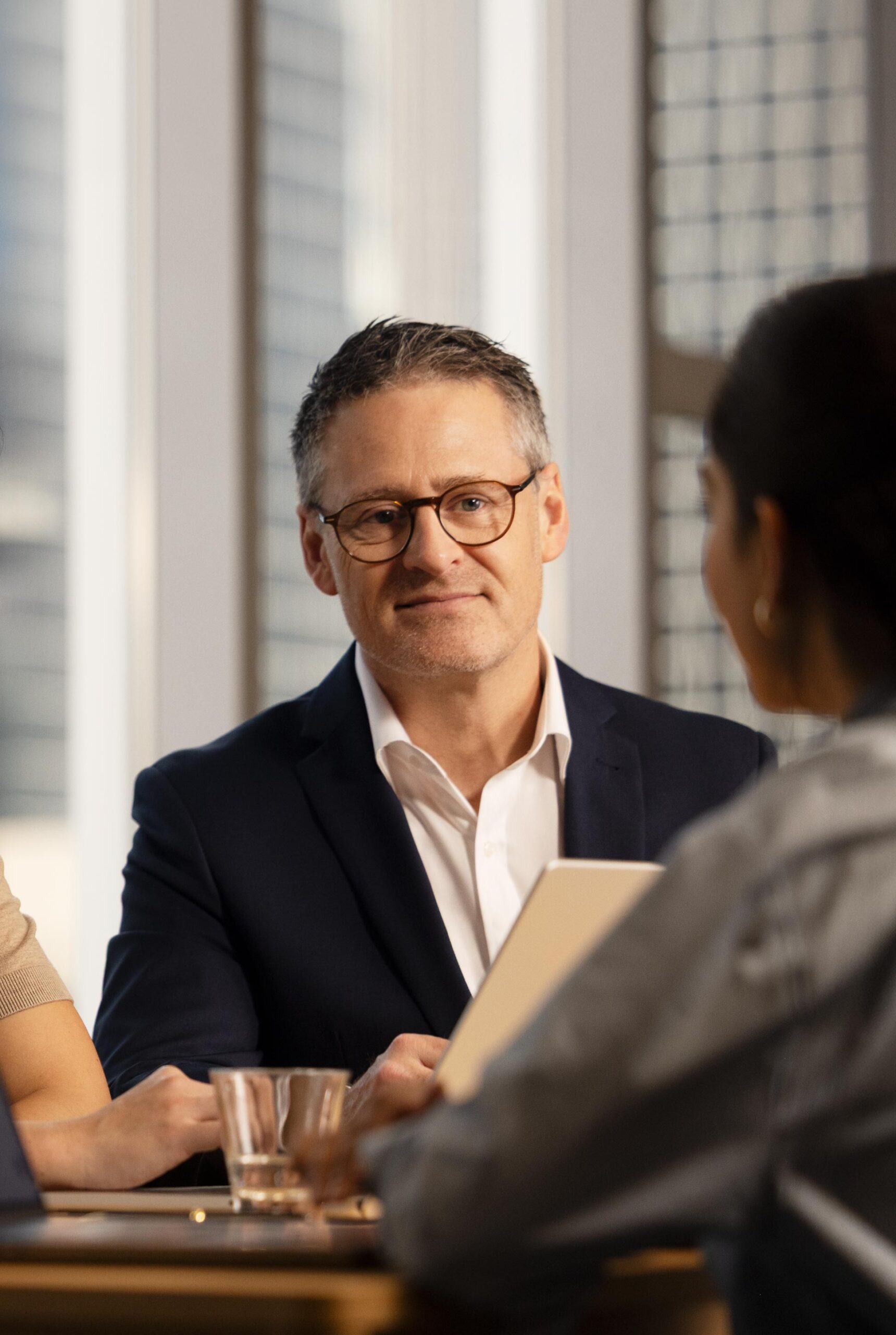A man look towards a young woman who is out of focus. They are mid conversation.