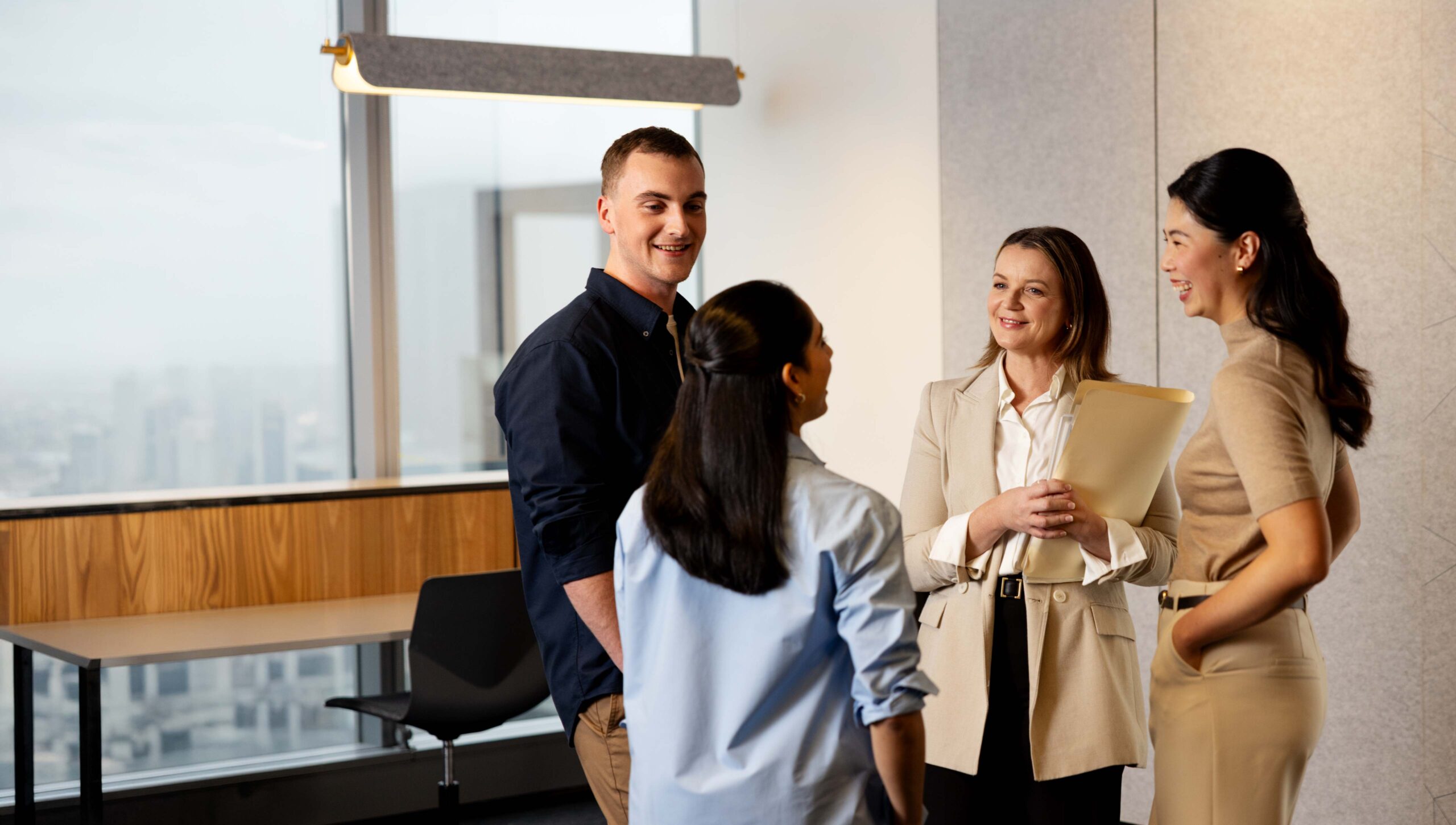 A group of four people, students and a teacher, talk together.